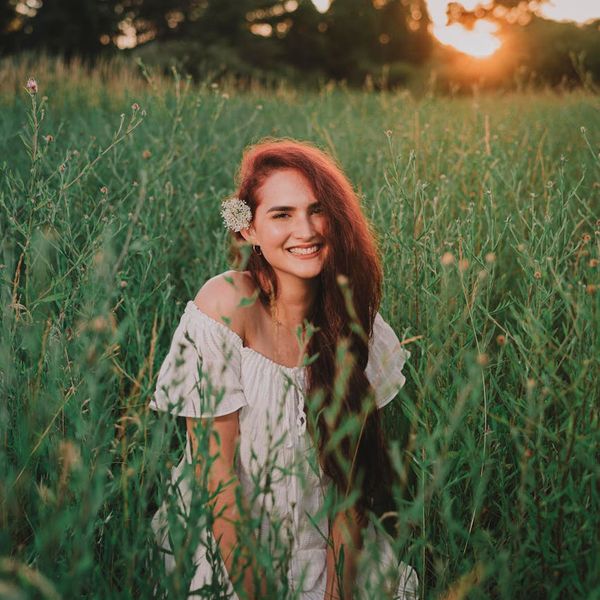 Person meditating peacefully in a bright, sunlit room with green plants.