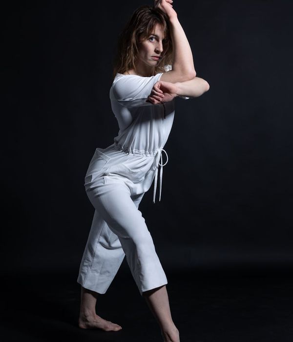 Woman performing a fluid yoga movement in a minimalist dark studio.
